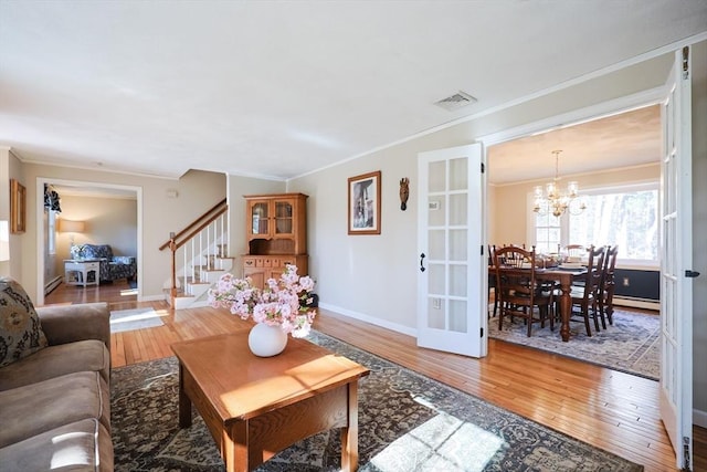 living room featuring crown molding, light wood finished floors, visible vents, stairway, and baseboards