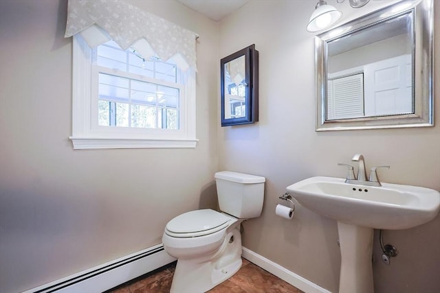 half bath featuring tile patterned flooring, toilet, a sink, baseboards, and baseboard heating