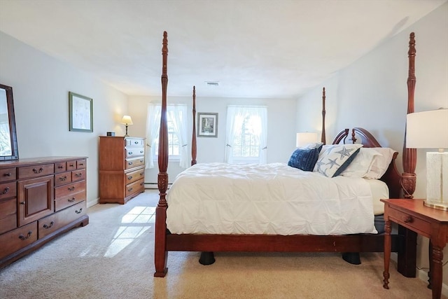 bedroom with a baseboard heating unit and light colored carpet