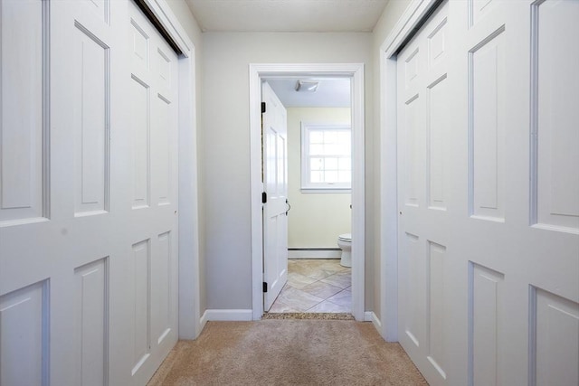 corridor featuring a baseboard radiator, light colored carpet, and baseboards