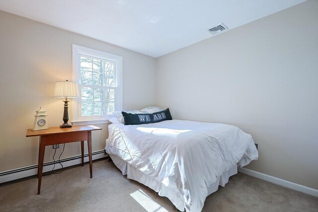 carpeted bedroom with a baseboard heating unit, visible vents, and baseboards