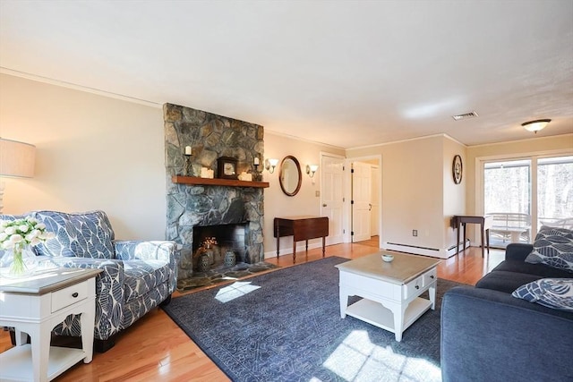 living room with a baseboard heating unit, visible vents, wood finished floors, and ornamental molding