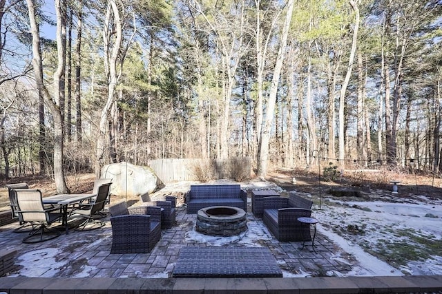 view of patio / terrace with a fire pit, fence, and a view of trees