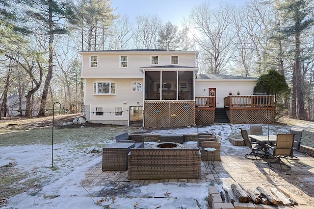 snow covered rear of property with outdoor dining area, an outdoor living space with a fire pit, a patio, a sunroom, and a wooden deck