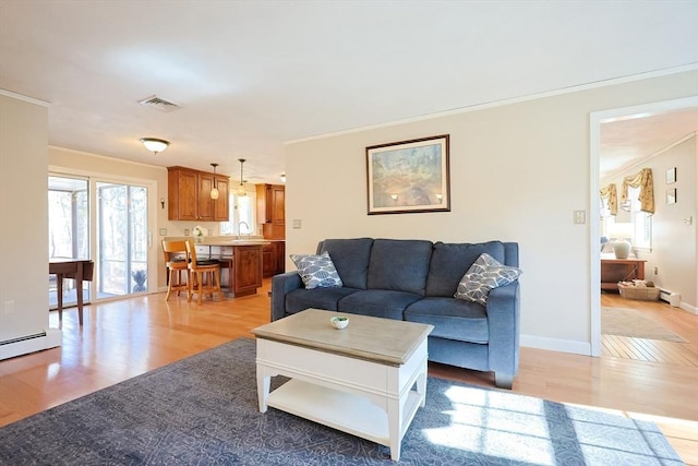 living room with a baseboard radiator, visible vents, light wood-style floors, ornamental molding, and baseboards