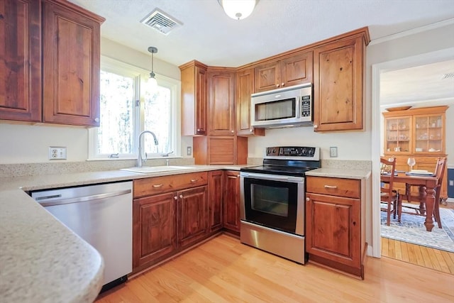 kitchen featuring light wood finished floors, visible vents, stainless steel appliances, and a sink