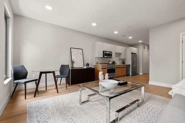 living area featuring light wood-type flooring, recessed lighting, and baseboards