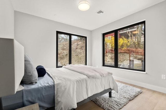 bedroom with visible vents, baseboards, and wood finished floors