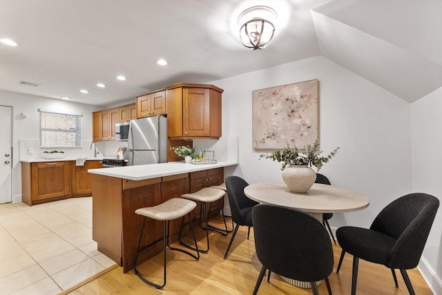 37 Symphony Rd Unit B, Boston, MA 02115 - kitchen featuring freestanding refrigerator, light countertops, brown cabinets, a peninsula, and recessed lighting