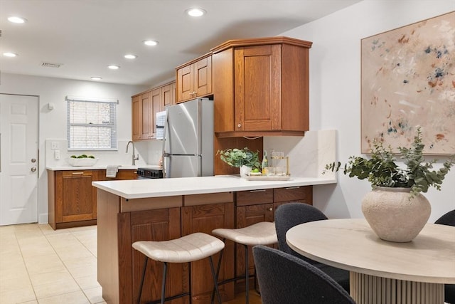 37 Symphony Rd Unit B, Boston, MA 02115 - kitchen with freestanding refrigerator, recessed lighting, a peninsula, brown cabinets, and light countertops