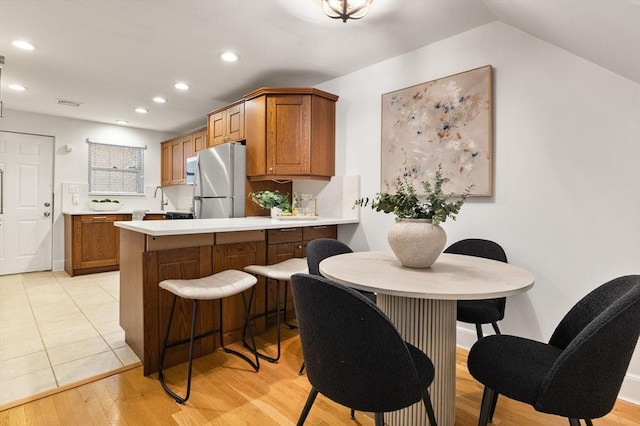 37 Symphony Rd Unit B, Boston, MA 02115 - kitchen featuring freestanding refrigerator, brown cabinetry, recessed lighting, light countertops, and a peninsula