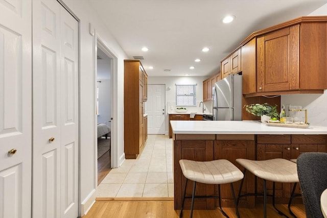 37 Symphony Rd Unit B, Boston, MA 02115 - kitchen featuring freestanding refrigerator, brown cabinets, a peninsula, recessed lighting, and light countertops