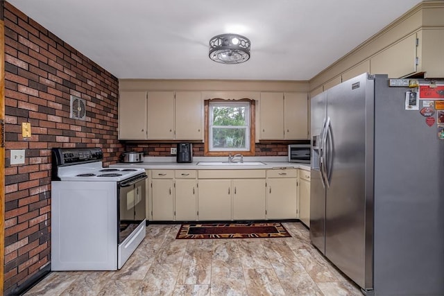 15 Winslow St, Gardner, MA 01440 - kitchen with stainless steel appliances, a sink, light countertops, cream cabinetry, and brick wall