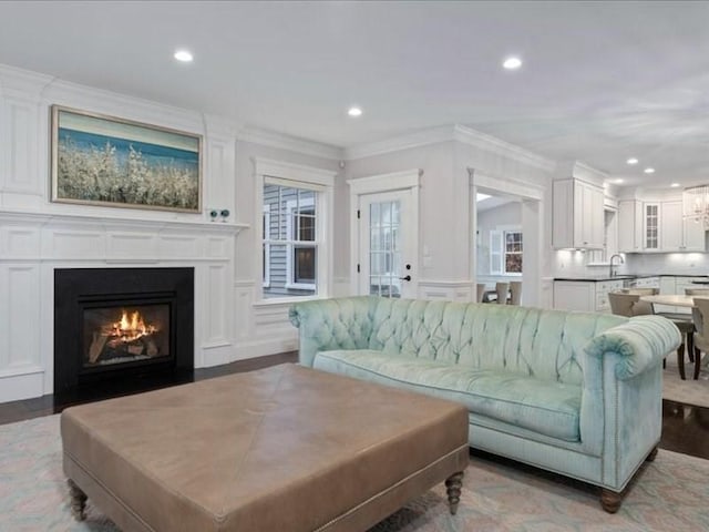 living room with hardwood / wood-style floors, sink, and crown molding