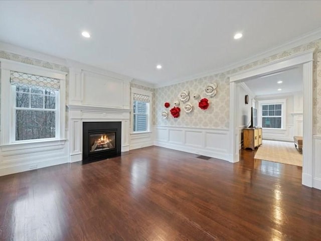 unfurnished living room with dark hardwood / wood-style floors, a wealth of natural light, and ornamental molding