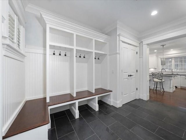 mudroom with dark tile patterned floors and ornamental molding