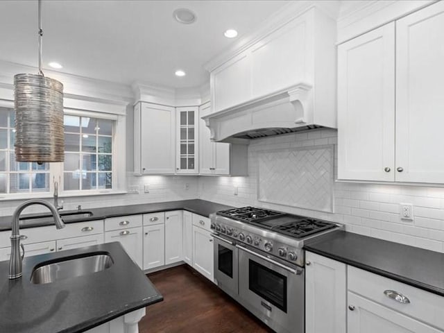 kitchen with decorative backsplash, white cabinetry, sink, and range with two ovens