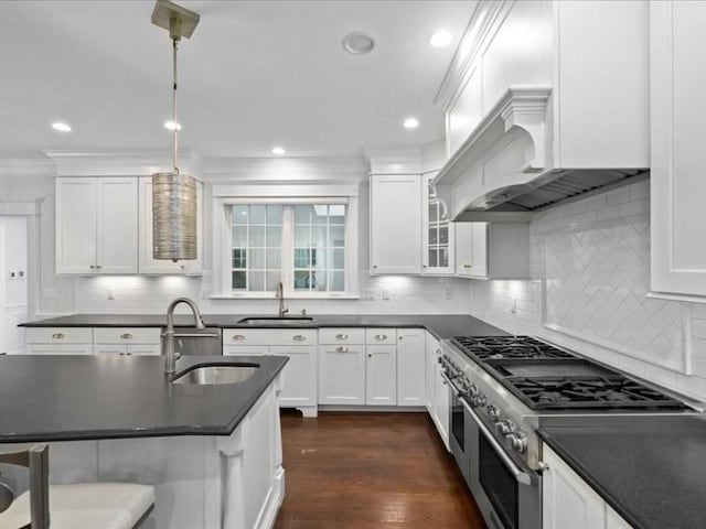 kitchen featuring white cabinetry, sink, hanging light fixtures, and range with two ovens