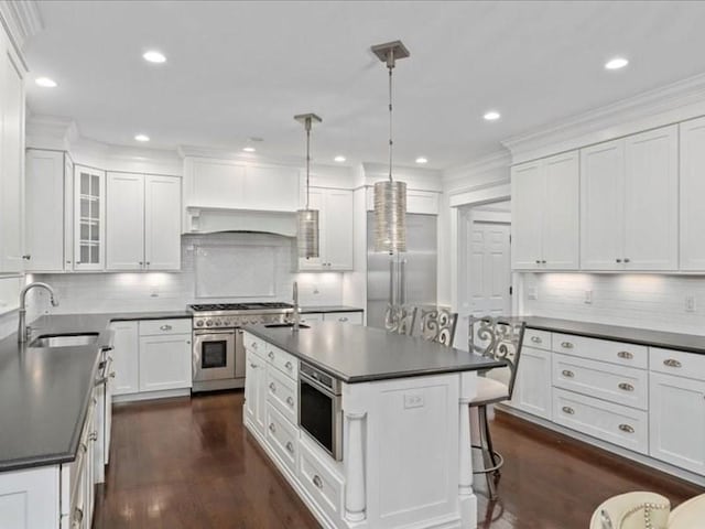 kitchen featuring pendant lighting, high quality appliances, white cabinetry, and sink