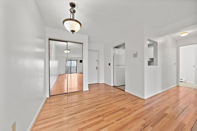 unfurnished room featuring light wood-style floors, baseboards, and a baseboard radiator