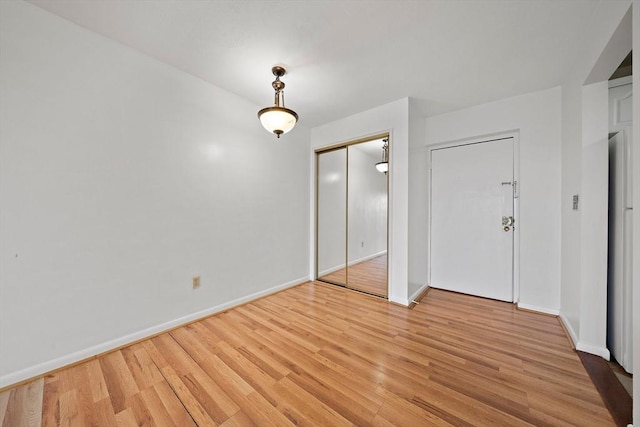 spare room with baseboards and light wood finished floors