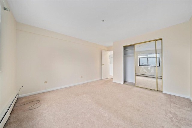 unfurnished bedroom featuring a closet, baseboard heating, light colored carpet, and baseboards