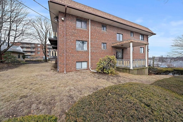 rear view of property with brick siding and a lawn