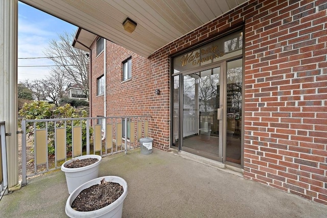 view of exterior entry with brick siding and a balcony