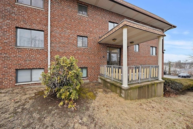 rear view of property featuring covered porch and brick siding