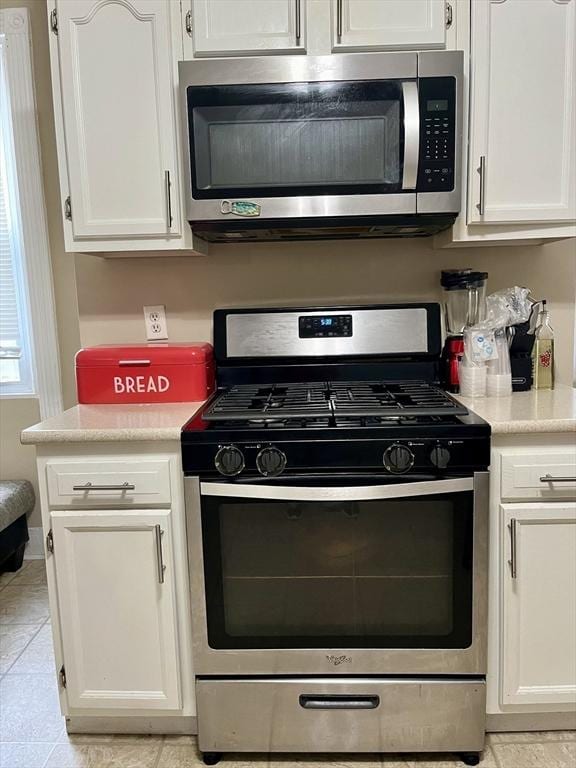 kitchen featuring light tile patterned flooring, appliances with stainless steel finishes, and white cabinets