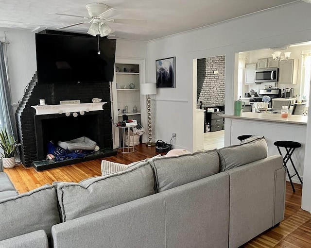 living room with built in shelves, wood-type flooring, and ceiling fan