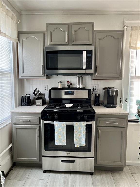 kitchen with tasteful backsplash, gray cabinets, and stainless steel appliances