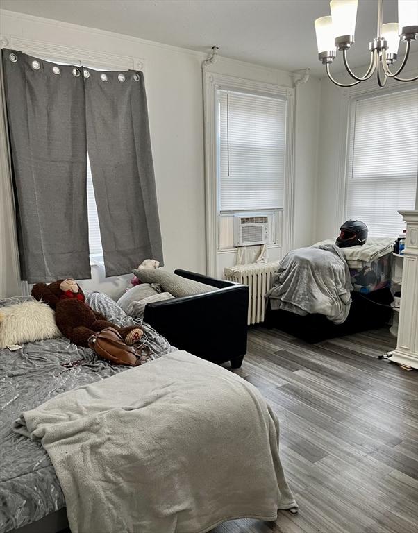 bedroom featuring radiator, cooling unit, a chandelier, hardwood / wood-style flooring, and ornamental molding