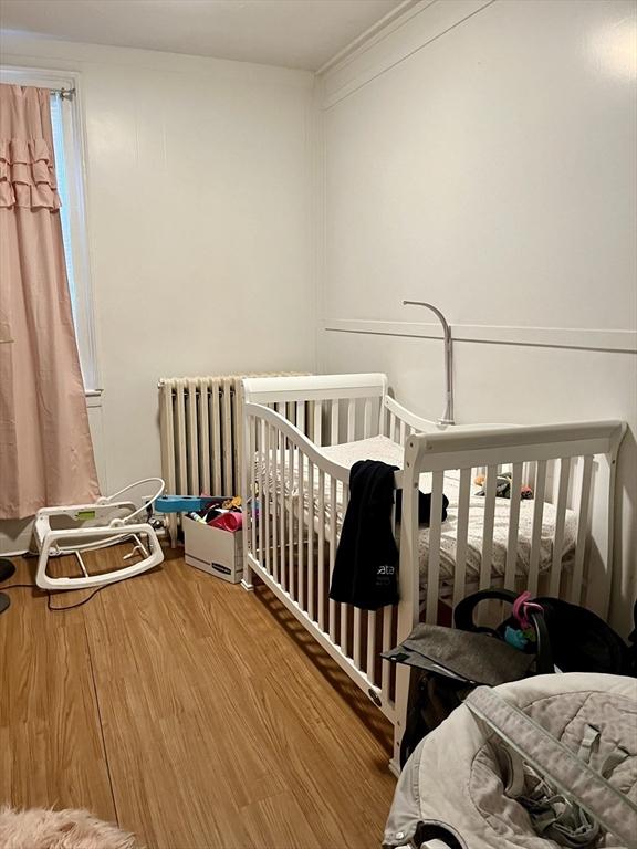 bedroom with a nursery area and hardwood / wood-style flooring