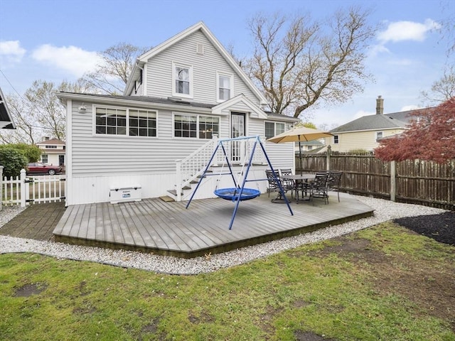 rear view of property featuring fence, a wooden deck, and outdoor dining area