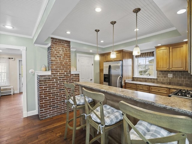 kitchen featuring appliances with stainless steel finishes, tasteful backsplash, a kitchen bar, and dark wood-type flooring