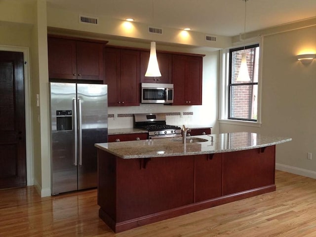191 Main St Unit 2B, Gloucester, MA 01930 - kitchen with appliances with stainless steel finishes, a sink, baseboards, a kitchen bar, and light wood-type flooring