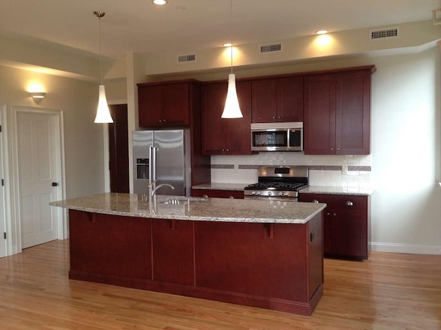 191 Main St Unit 2B, Gloucester, MA 01930 - kitchen featuring appliances with stainless steel finishes, a sink, decorative backsplash, light wood-style floors, and baseboards