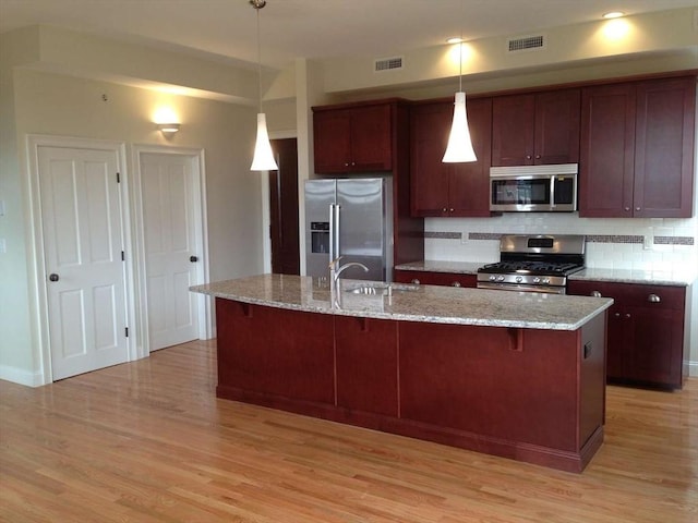 191 Main St Unit 2B, Gloucester, MA 01930 - kitchen with appliances with stainless steel finishes, decorative backsplash, light wood-style floors, and hanging light fixtures