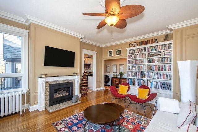 sitting room featuring ceiling fan, dark hardwood / wood-style floors, radiator heating unit, and ornamental molding