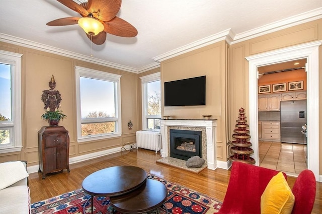 living room featuring hardwood / wood-style flooring, radiator heating unit, and crown molding