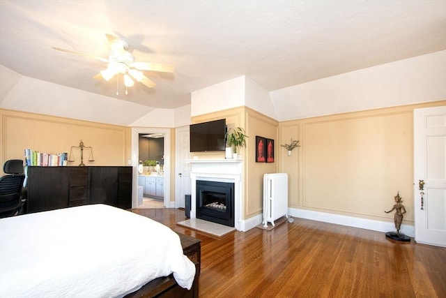 bedroom featuring radiator heating unit, wood-type flooring, vaulted ceiling, ceiling fan, and ensuite bathroom