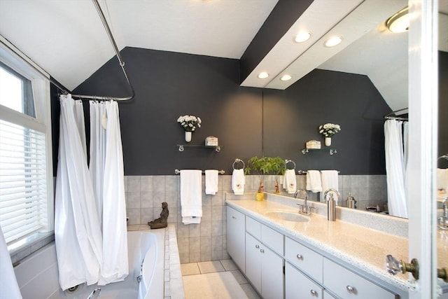 bathroom featuring tile patterned flooring, vaulted ceiling, tile walls, vanity, and shower / bathtub combination with curtain