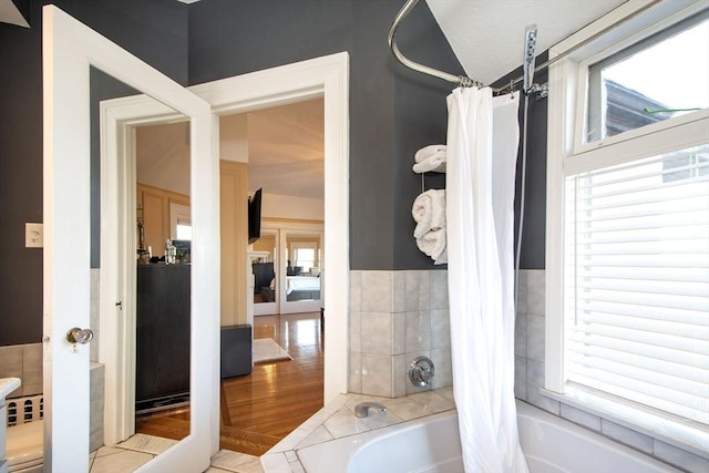 bathroom featuring shower / tub combo, plenty of natural light, and tile walls