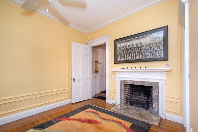 living room with a fireplace, hardwood / wood-style flooring, ceiling fan, and ornamental molding