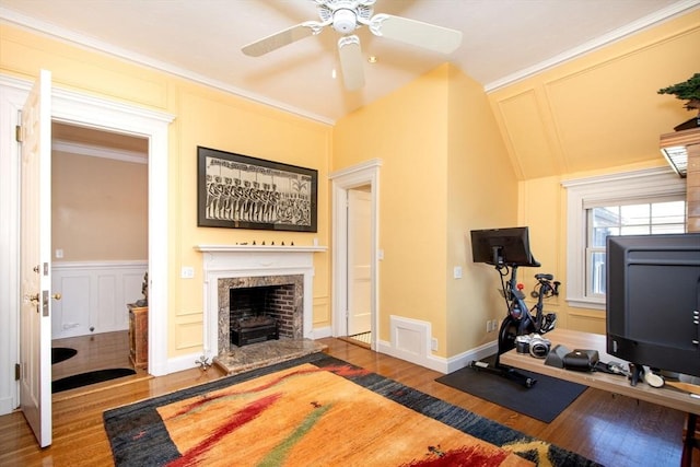 workout area featuring a fireplace, wood-type flooring, ornamental molding, ceiling fan, and lofted ceiling