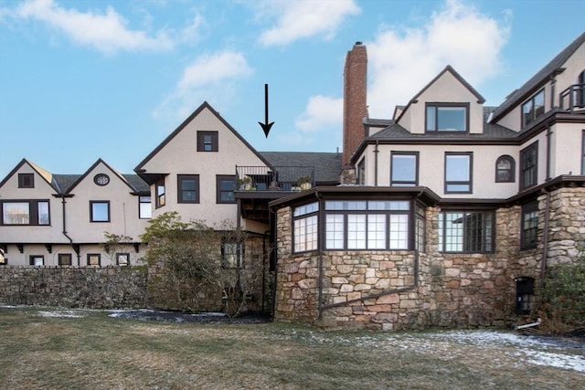 back of house featuring a balcony and a yard