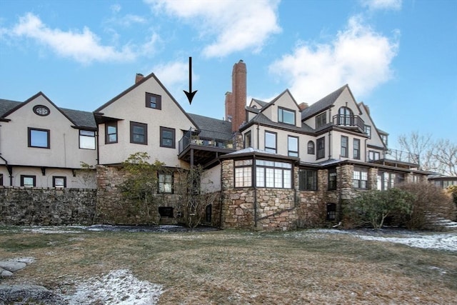 back of property featuring a balcony and a yard