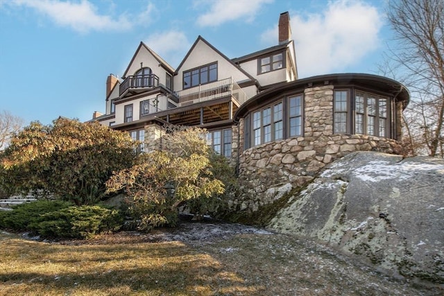 view of front of house featuring a balcony and a front lawn