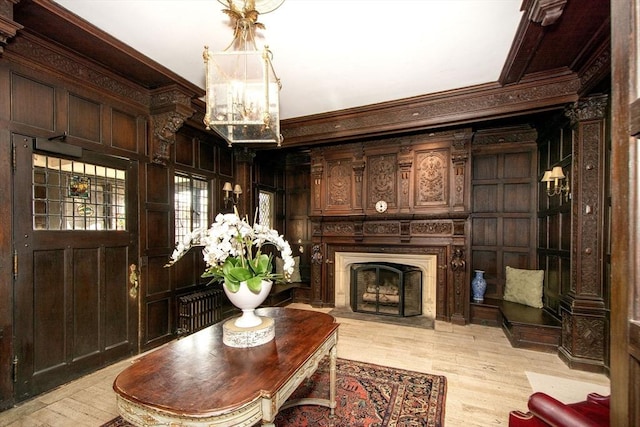 living area featuring crown molding, wood walls, light hardwood / wood-style flooring, and a notable chandelier